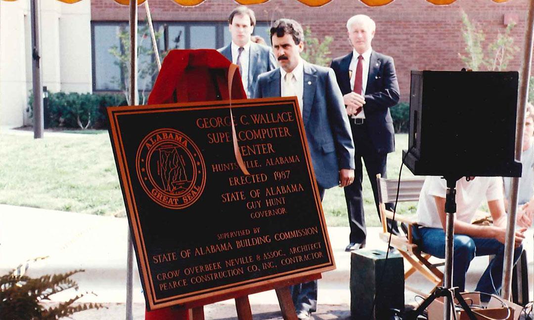 Outdoor photo of unveiled bronze dedication plaque on an easel naming the Alabama Supercomputer Center after governor George C. Wallace