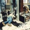 Two men working on wiring up the Cray XMP on datacenter floor with numerous bundles of wiring on the floor and removed floor tiles exposing electrical and cooling system conduits 